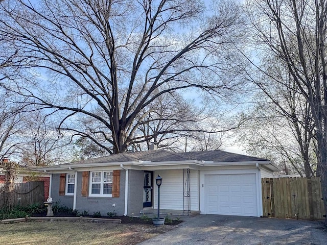 view of front of house with brick siding, an attached garage, and fence