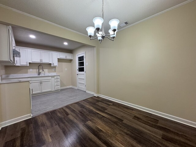 kitchen with an inviting chandelier, light countertops, dark wood-type flooring, pendant lighting, and a textured ceiling