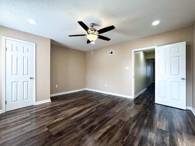 unfurnished bedroom featuring a textured ceiling, dark wood-style floors, visible vents, and baseboards