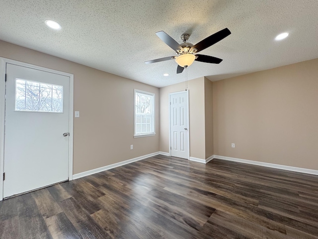 foyer entrance featuring baseboards, dark wood-type flooring, a ceiling fan, and a textured ceiling