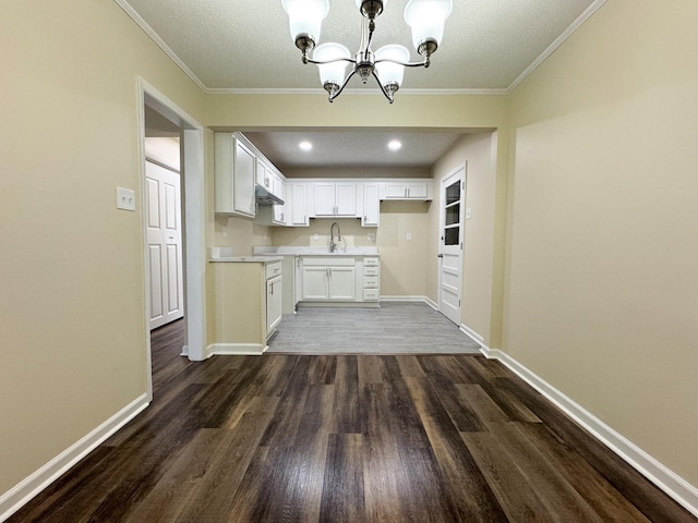 kitchen featuring a notable chandelier, a sink, dark wood-style floors, white cabinets, and light countertops