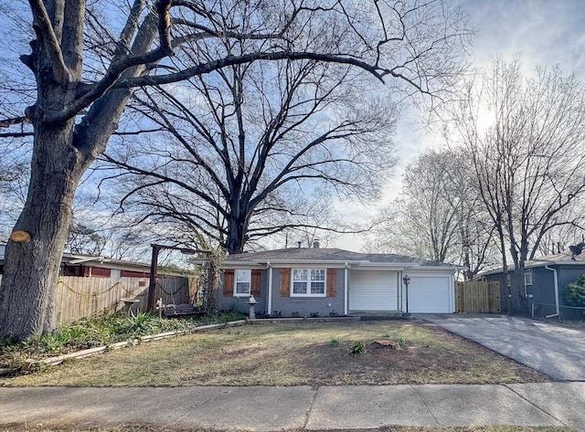 view of front of house with driveway, brick siding, an attached garage, and fence