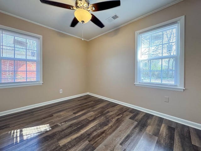 spare room with a wealth of natural light, visible vents, dark wood finished floors, and ornamental molding