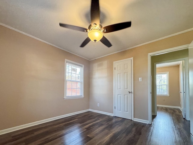 unfurnished bedroom with dark wood-type flooring, multiple windows, and crown molding