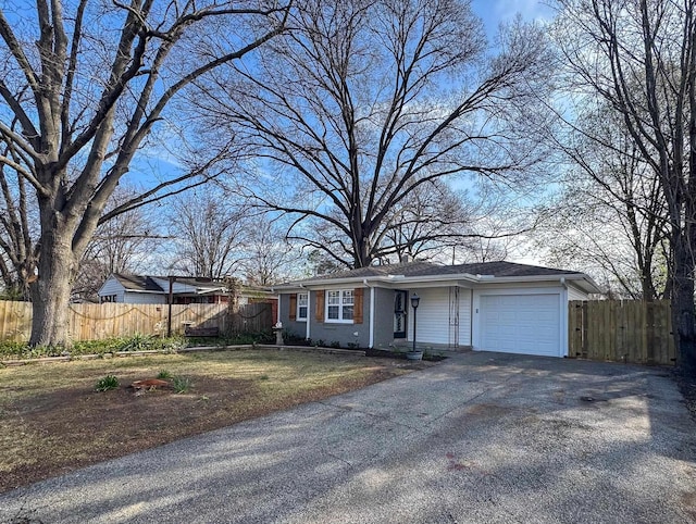 ranch-style house featuring a garage, aphalt driveway, brick siding, and fence