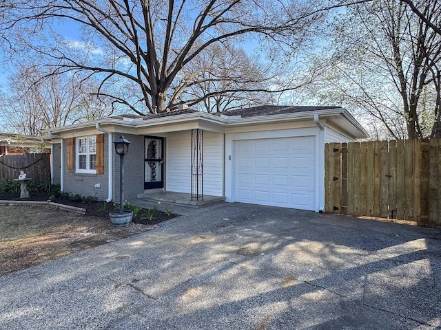 ranch-style home featuring a garage, fence, brick siding, and driveway