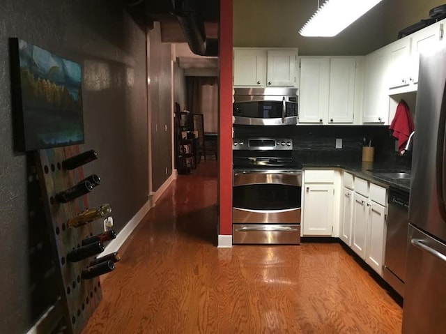 kitchen with dark countertops, dark wood-style floors, white cabinets, and appliances with stainless steel finishes