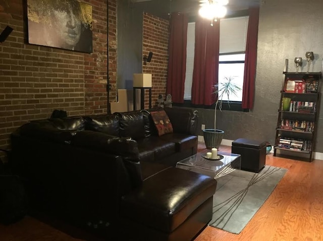 living room featuring brick wall and wood finished floors