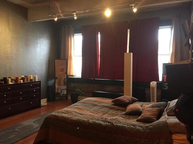 bedroom featuring track lighting and wood finished floors