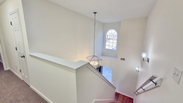 interior space featuring carpet, baseboards, visible vents, an upstairs landing, and a chandelier