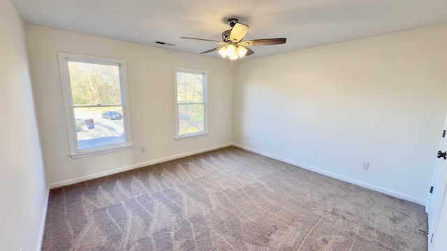 carpeted empty room featuring visible vents, a ceiling fan, and baseboards