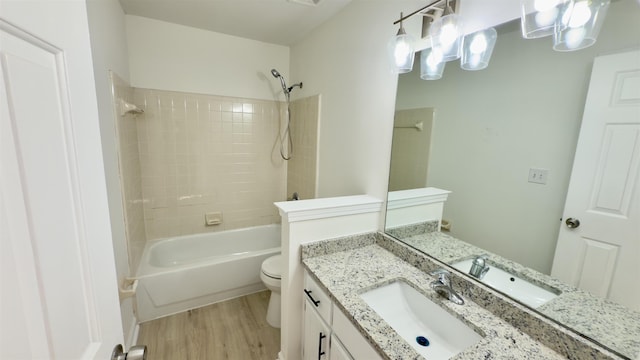 bathroom with toilet,  shower combination, wood finished floors, and vanity