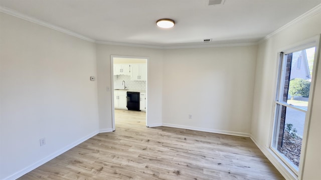 unfurnished room with visible vents, baseboards, light wood-style floors, and ornamental molding