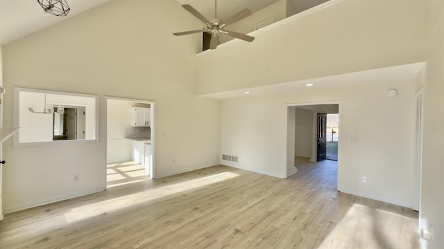 interior space with light wood-type flooring, visible vents, high vaulted ceiling, baseboards, and ceiling fan