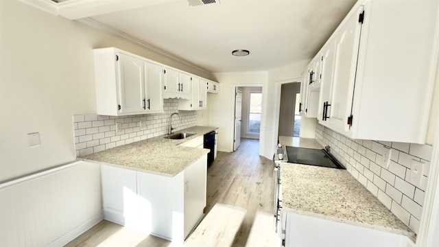 kitchen featuring crown molding, light wood-style flooring, stainless steel range with electric cooktop, white cabinets, and a sink