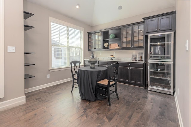 dining space with lofted ceiling, beverage cooler, dark wood-type flooring, and baseboards