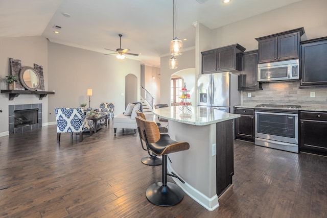 kitchen featuring a kitchen bar, arched walkways, appliances with stainless steel finishes, and open floor plan