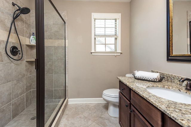 bathroom with vanity, a shower stall, toilet, and baseboards