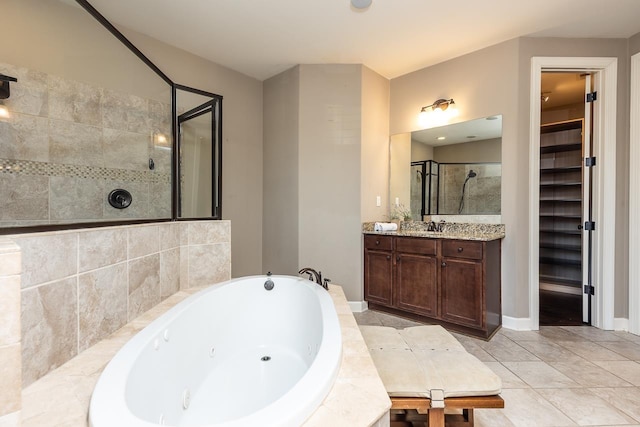 full bathroom featuring a jetted tub, a walk in closet, tiled shower, tile patterned floors, and vanity