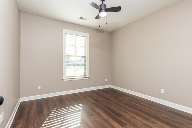 empty room featuring ceiling fan, dark wood-style floors, visible vents, and baseboards