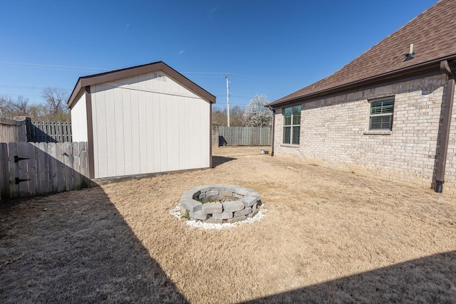 view of yard featuring a fire pit, fence private yard, a shed, and an outdoor structure