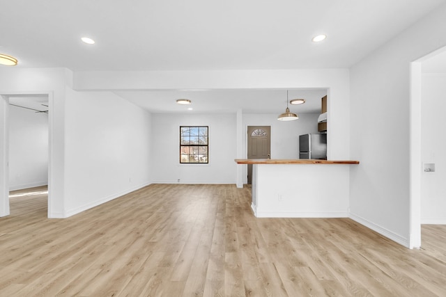 unfurnished living room featuring recessed lighting, baseboards, and light wood finished floors