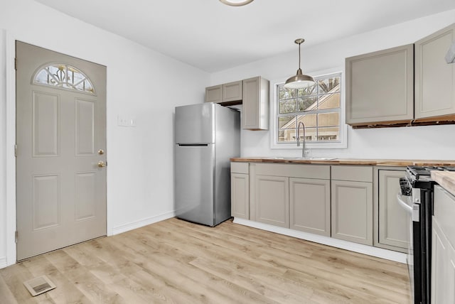 kitchen with wooden counters, stainless steel appliances, light wood-style floors, and a sink