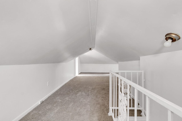 hall with baseboards, lofted ceiling, carpet, and an upstairs landing