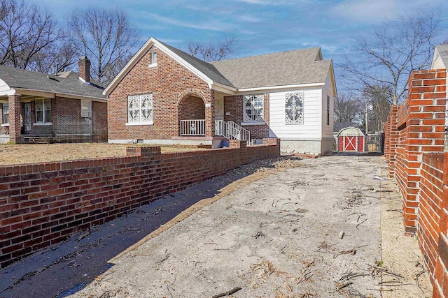 view of front of house with brick siding, driveway, and a gate