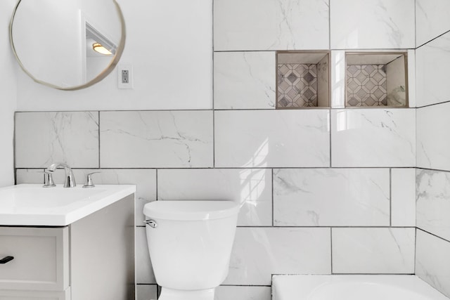 bathroom with vanity, toilet, and a tub