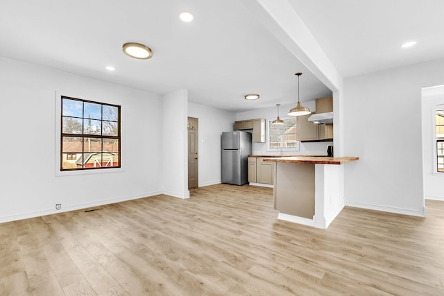 kitchen featuring light wood-style floors, baseboards, freestanding refrigerator, and wooden counters