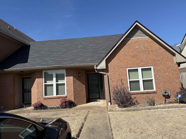 view of front facade with brick siding and roof with shingles