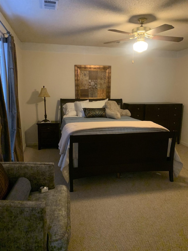 bedroom with visible vents, light colored carpet, a textured ceiling, and a ceiling fan