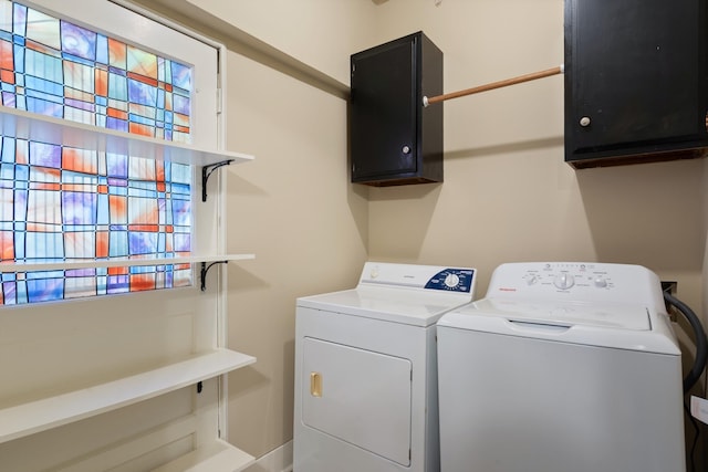 clothes washing area featuring washer and dryer and cabinet space