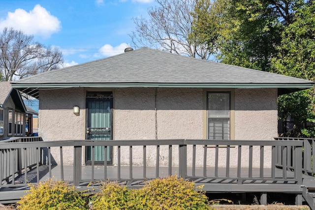 rear view of property featuring stucco siding and roof with shingles