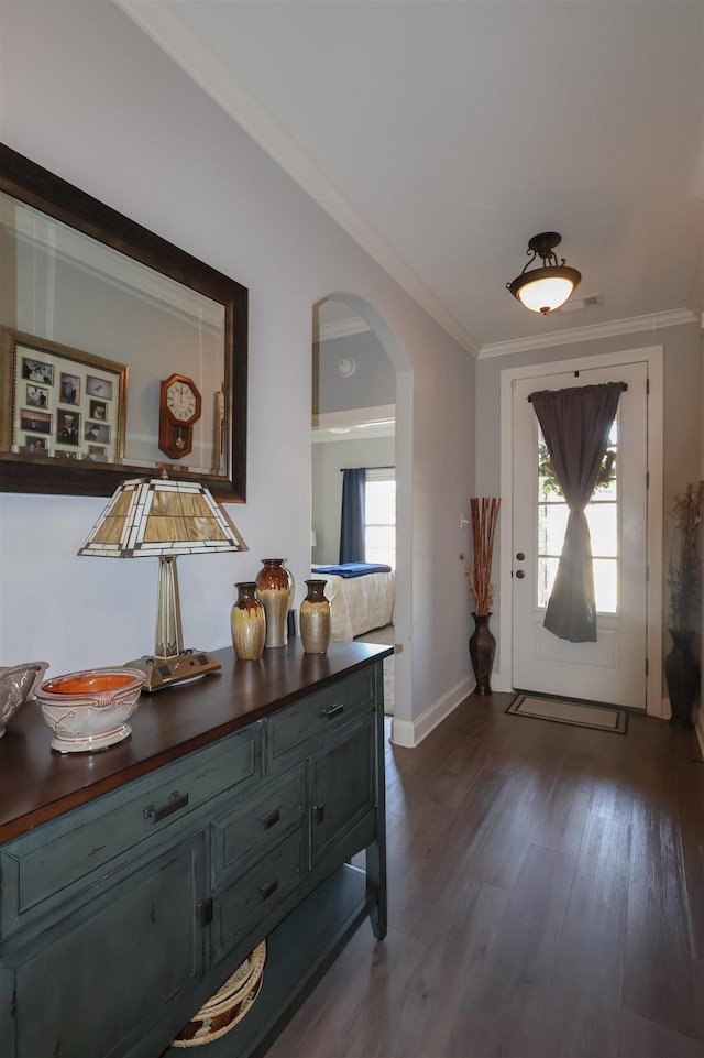 foyer entrance with arched walkways, a healthy amount of sunlight, ornamental molding, and dark wood-style flooring