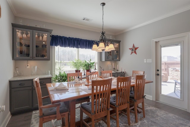 dining room with visible vents, wood finished floors, ornamental molding, and a chandelier