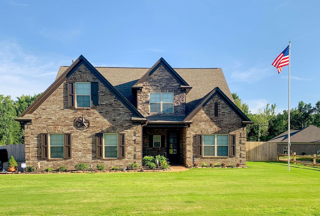 craftsman house featuring brick siding, a front yard, and fence