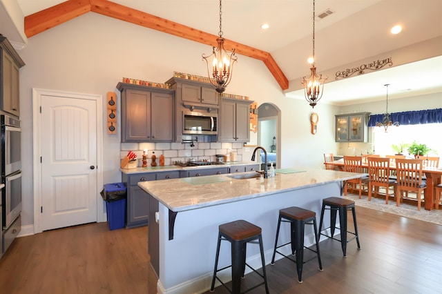kitchen with a kitchen breakfast bar, tasteful backsplash, stainless steel appliances, light stone countertops, and a chandelier