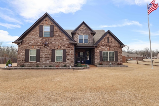 craftsman inspired home with brick siding, a front yard, and fence