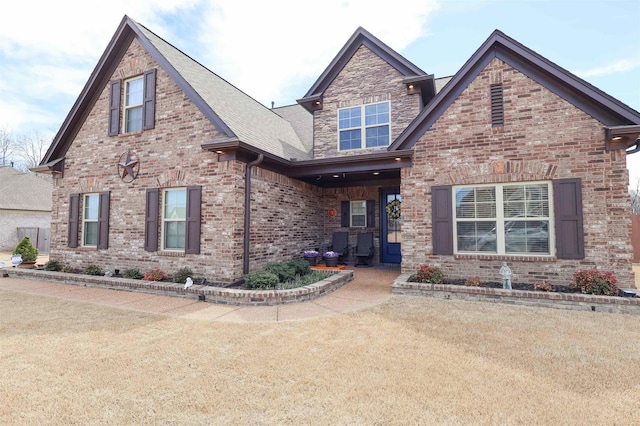 view of front facade with brick siding and a front lawn
