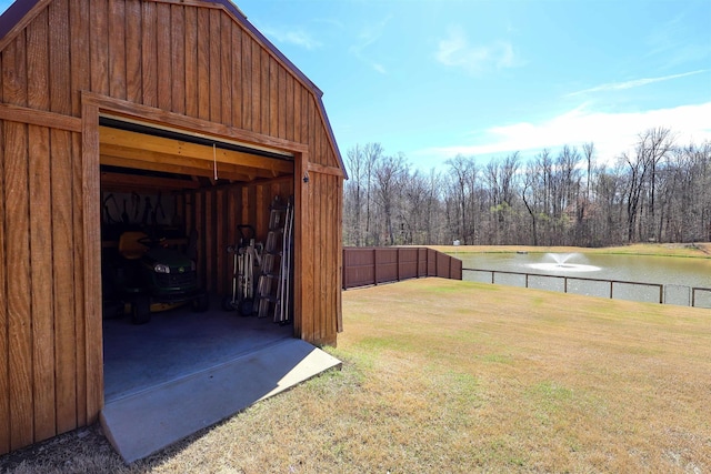 view of outdoor structure featuring fence, an outdoor structure, and a water view