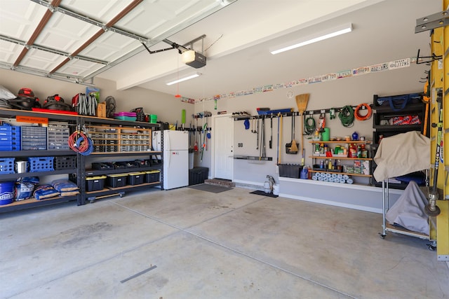 garage featuring a workshop area, a garage door opener, and freestanding refrigerator