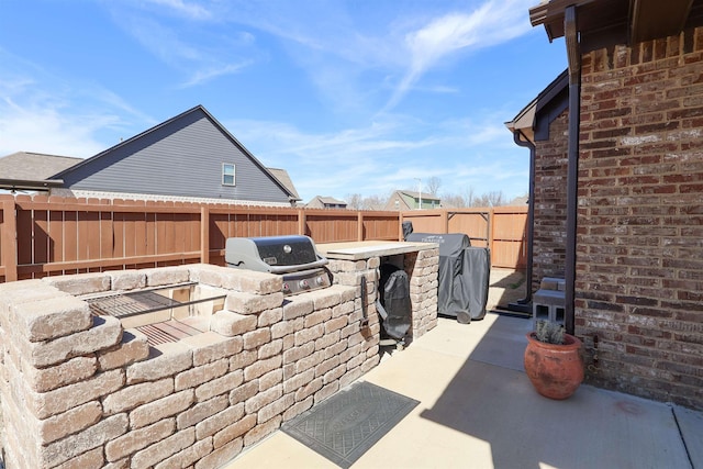 view of patio / terrace featuring a grill, a fenced backyard, and exterior kitchen