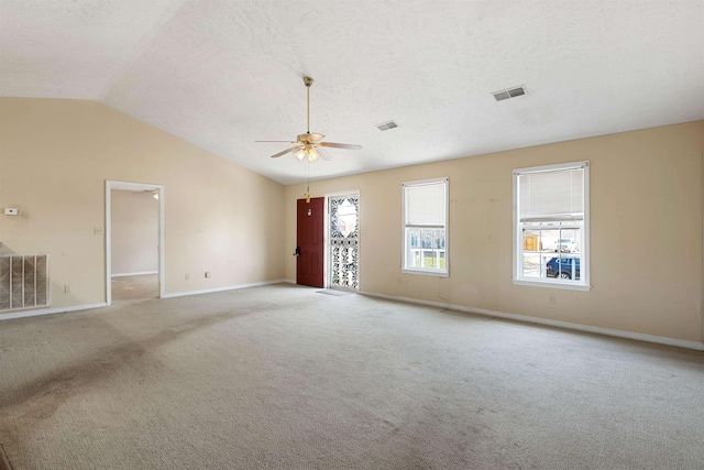 spare room with a textured ceiling, vaulted ceiling, visible vents, and ceiling fan