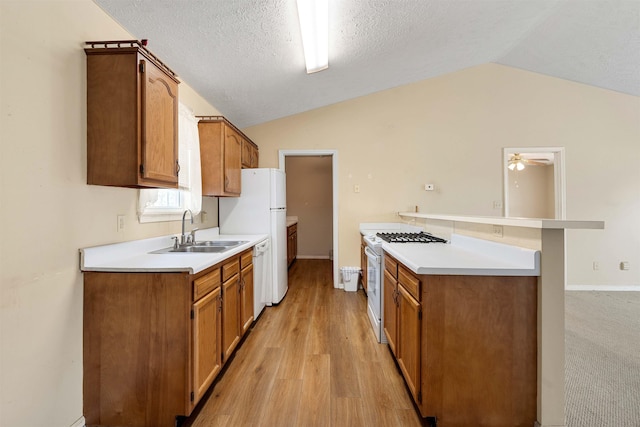 kitchen featuring light countertops, lofted ceiling, brown cabinets, white appliances, and a sink