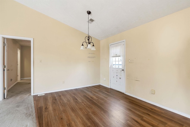 empty room featuring wood finished floors, visible vents, baseboards, an inviting chandelier, and lofted ceiling