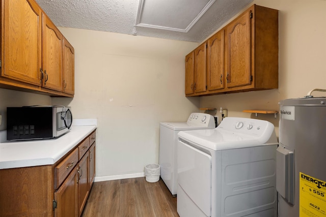 washroom with electric water heater, a textured ceiling, washing machine and dryer, dark wood finished floors, and baseboards