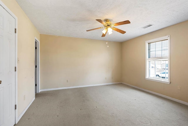 spare room with a textured ceiling, light carpet, visible vents, and ceiling fan