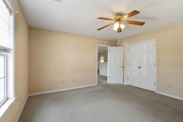 unfurnished bedroom with multiple windows, a textured ceiling, and carpet floors